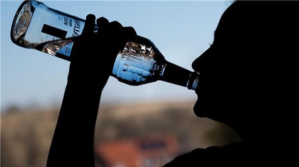 Ein Mädchen trinkt in ihrem Zimmer eine Flasche Wodka.