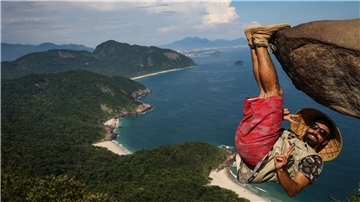 Ein Mann hängt für ein Bild an dem Felsen „Pedra do Telegrafo“ bei Rio de Janeiro.