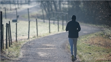 Ein Mann joggt über einen Feldweg am Morgen.