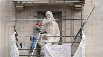 Ein Mann mit einer Spiderman-Maske beschädigt die Statue eines umstrittenen Bildhauers am Hauptquartier der BBC in London.