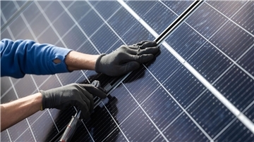 Ein Mann montiert Photovoltaikmodule auf das  Dach eines Wohnhauses.