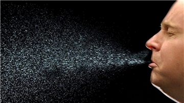 Ein Mann niest. Beim Niesen fliegen viele Tröpfchen durch die Luft. Auf diese Weise kann sich auch das neuartige Coronavirus Sars-CoV-2 verbreiten.