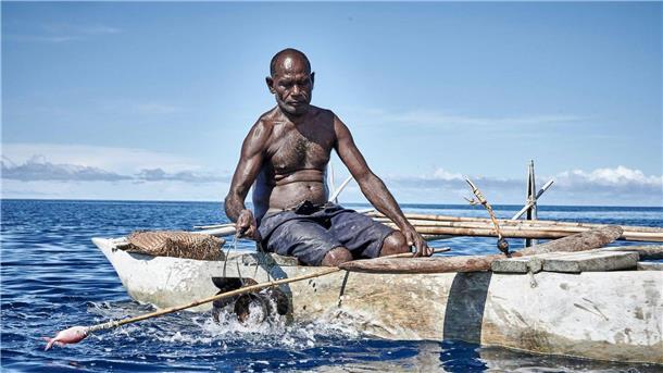 Ein Mann sitzt beim „Shark Calling Festival“ in einem Boot. Auf der Insel vor Papua-Neuguinea rufen Einheimische gefährliche Haie mit Liedern und Rasseln.
