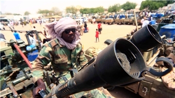 Ein Milizionär sitzt neben militärischer Ausrüstung, die angeblich während eines Gefechts im umkämpften Gebiet in Süd-Darfur erbeutet wurde.