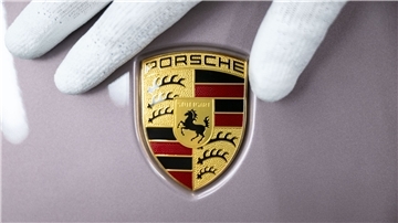 Ein Mitarbeiter der Porsche AG zeigt das Porsche-Logo.