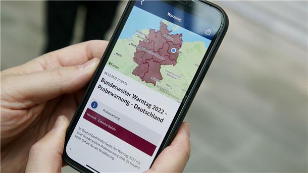 Warntag mit Fehlern: Probealarm erreicht nicht alle Handys Ein Mitarbeiter des Bundeskanzleramts hält sein Mobiltelefon in der Hand.
