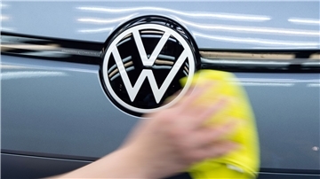 Ein Mitarbeiter von Volkswagen streicht mit einem Tuch über ein Fahrzeug von VW.