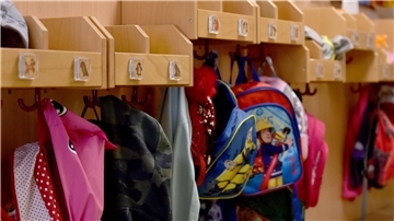 An Kleiderhaken hängen Jacken und Rucksäcke von Kindergartenkindern.
