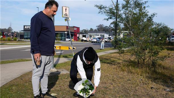 Nach Busunglück mit zehn Toten - Busfahrer freigelassen Ein Paar legt Blumen an einer Straßensperre in der Nähe des Unglücksortes nördlich von Sydney ab.