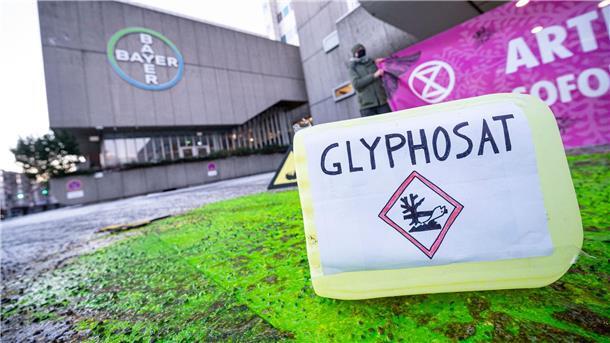 Zehn weitere Jahre - Was es mit Glyphosat auf sich hat Ein Plastikcontainer mit der Aufschrift „Glyphosat“ steht bei einer Protestaktion vor dem Eingang des Chemiekonzerns Bayer. Das Mittel bleibt zugelassen.