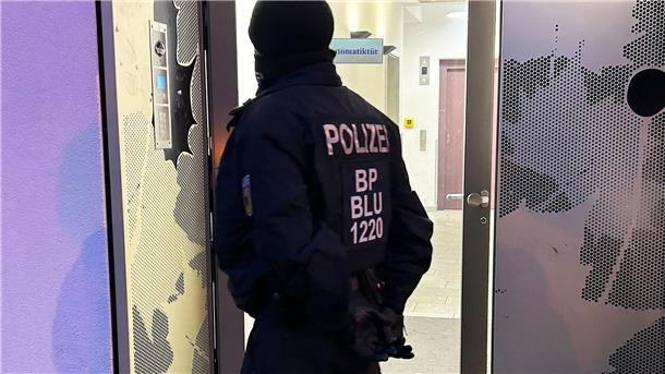 Drei Wochen nach Verbot: Razzien bei Hamas und Samidoun Ein Polizeibeamter steht bei einer Razzia in Berlin-Adlershof vor einem Gebäude.