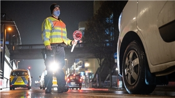 Ein Polizeibeamter winkt im Dezember 2020 während einer Verkehrskontrolle zur Einhaltung der coronabedingten Ausgangsbeschränkungen in Stuttgart ein Auto raus. Ab morgen gilt eine solche Regelung in der Wesermarsch.