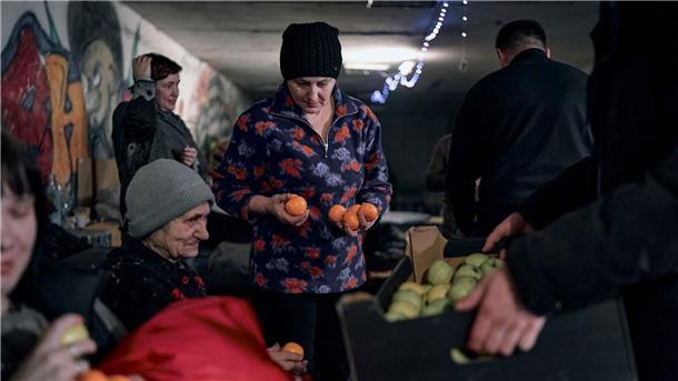 Krieg gegen die Ukraine: So ist die Lage Ein Polizist in Awdijiwka beschenkt Menschen mit Mandarinen und Äpfeln in der Vorweihnachtszeit in einem als Bunker genutzten Keller eines Wohnhauses.