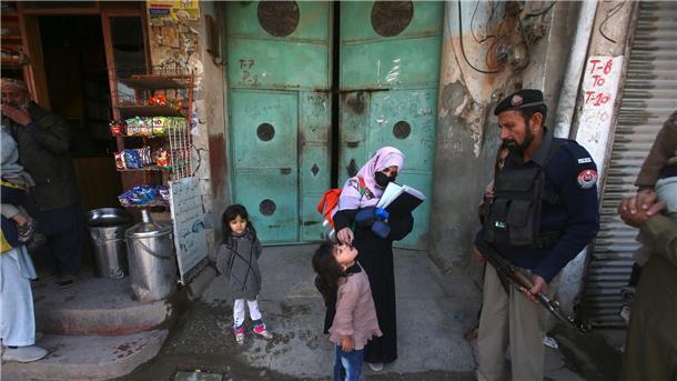 Pakistan meldet ersten Polio-Fall in diesem Jahr Ein Polizist in Pakistan steht Wache, während einem Kind ein Polio-Impfstoff verabreicht wird.
