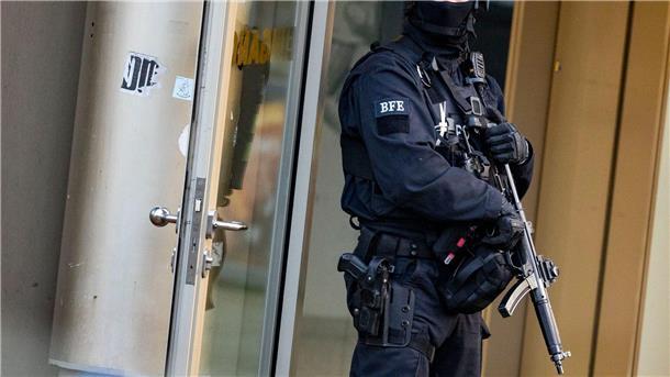 Ein Polizist steht mit einer Maschinenpistole am Tatort.