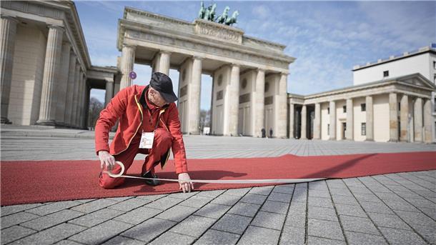 Jubelrufe und Fähnchen: Charles und Camilla in Berlin Ein roter Teppich wird vor dem Brandenburger Tor für die britischen Royals ausgerollt.