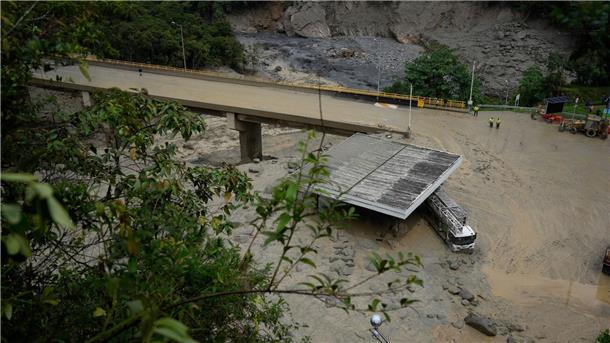Ein schlammbedeckter Lastwagen steht nach einem Erdrutsch unter einer Brücke.