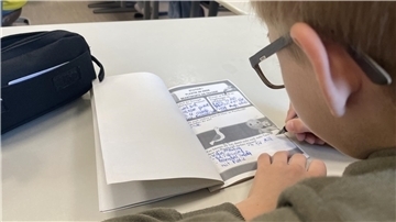Ein Schüler schreibt etwas auf.