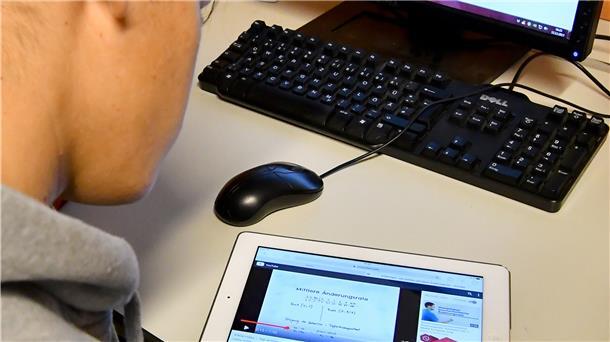 Ein Schüler löst eine Aufgabe mit iPad und Computer. Auch in den Schulen sind digitale Lernmittel auf dem Vormarsch.