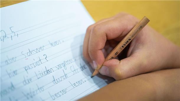 Schreiben mit der Hand Ein Schüler schreibt mit einem Bleistift.