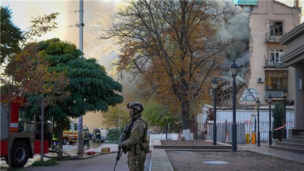 Wieder Luftangriffe auf die Ukraine Ein Soldat steht Wache, während Feuerwehrleute an dem Ort arbeiten, an dem eine Drohne auf Gebäude geschossen hat.