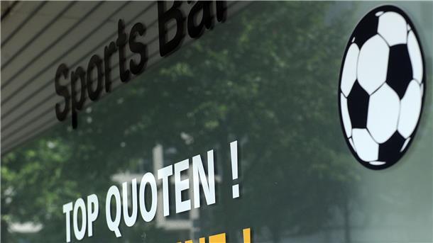 Ein Sportwettenladen wirbt mit aufgeklebten Slogans an einer Fensterscheibe.