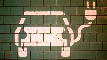 Ein Symbol markiert einen Parkplatz mit einer öffentlichen Ladesäule für Elektroautos.
