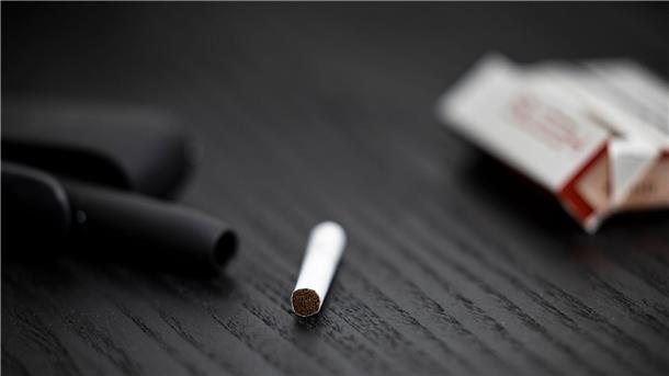 Ein Tabakstick, Stickpäckchen und Tabakerhitzer liegen auf einem Tisch. Die drei Branchenriesen haben hohe Erwartungen an den künftigen Absatz.