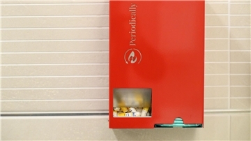 Ein Tampon- und Bindenspender von „Periodically“ hängt auf einer Damentoilette