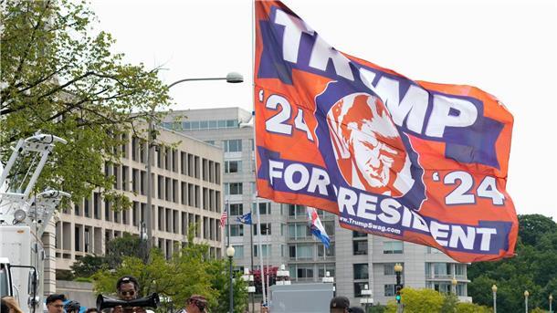 Ein Trump-Unterstützer hat eine riesige Flagge mit zum Gerichtsgebäude in Washington gebracht, wo der Ex-Präsident persönlich erscheinen soll.
