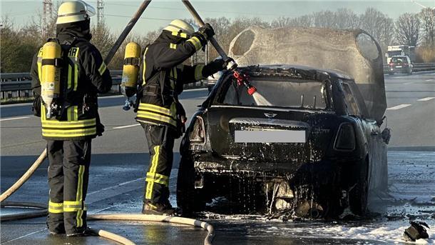 Feuerwehrleute löschen ein Fahrzeug auf einer Autobahn