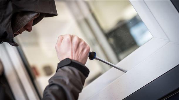 Urlaubszeit ist Einbruchszeit: So schützen Sie Ihr Zuhause Ein Einbrecher hebelt mit einem Schraubendreher ein Fenster auf
