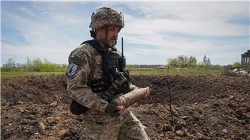 Ein ukrainischer Soldat sammelt nicht explodierte Granaten ein.