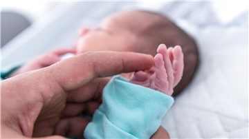 Ein Vater hält die Hand eines wenige Tage alten Jungen. In der Helios-Klinik Cuxhaven gibt es derzeit nicht genügend Ärzte, um die Geburtshilfe und den Bereich Kinder- und Jugendmedizin durchgängig zu besetzen.