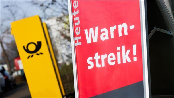Post-Warnstreiks: Jeder zehnte Brief bleibt vorerst liegen Ein Warnstreik-Schild bei einem Post-Standort, daneben ein Briefkasten - im Ringen um einen Tarifabschluss haben Tausende Postler erneut die Arbeit niedergelegt.