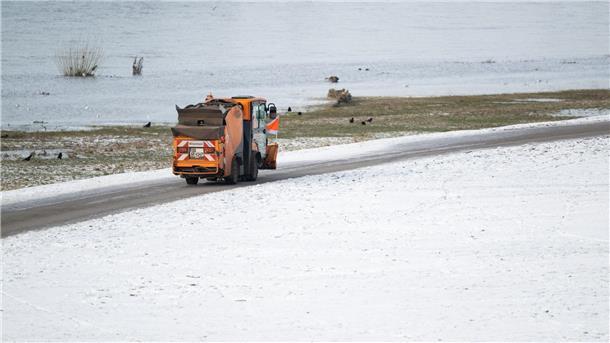 Winterwetter bremst Verkehr in Teilen Deutschlands aus Ein Winterdienst-Fahrzeug fährt auf dem Radweg an den verschneiten Elbwiesen in Dresden entlang.
