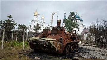 Ein zerstörter russischer Schützenpanzer steht vor einer Kirche in Isjum.