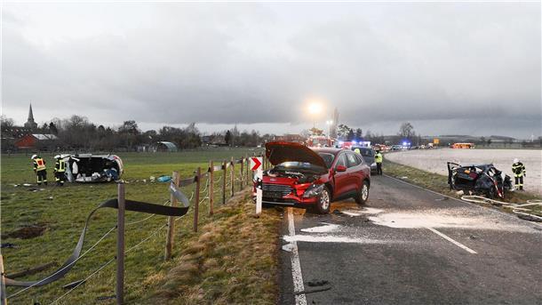 Ein zerstörtes Auto (l) liegt auf einer Wiese.