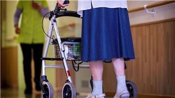 Eine ältere Dame geht mit ihrem Rollator über einen Flur.