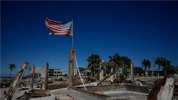 Wirbelsturm „Ian“ verliert an Kraft  Eine amerikanische Flagge weht inmitten durch den Hurrikan „Ian“ zerstörten Geschäften am Strand von Fort Myers in Florida.