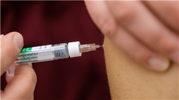 Eine Arzthelferin impft in einer Arztpraxis eine Patientin mit einer Spritze.