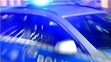Ein Streifenwagen der Polizei steht mit eingeschaltetem Blaulicht auf der Straße.