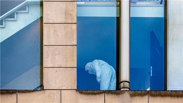 Eine Beamtin der Polizei untersucht in Schutzkleidung das Treppenhaus.