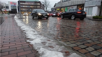 Autos fahren auf einer Straße mit Restschnee am Straßenrand