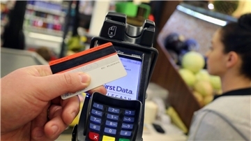 Eine EC-Karte wird an den Bezahl-Terminal an der Kasse eines Supermarktes gehalten.
