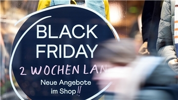 Eine Frau geht an einem Geschäft vorbei, das mit Black Friday-Angeboten wirbt.
