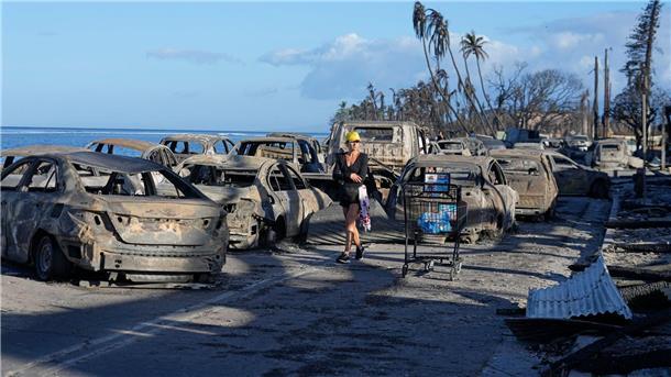 Eine Frau geht an zurückgebliebenen Trümmern nach dem Waldbrand in Lahaina vorbei.