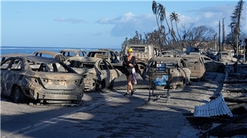 Eine Frau geht an zurückgebliebenen Trümmern nach dem Waldbrand in Lahaina vorbei.