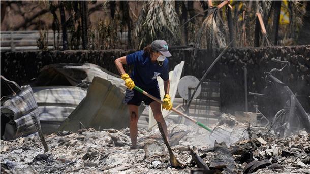 Eine Frau gräbt in Lahaina auf Hawaii in den Trümmern eines zerstörten Hauses.