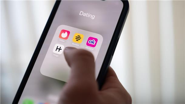 Studie zu Online-Dating: Männer wollen hoch hinaus Eine Frau hält ein Smartphone, auf dem Dating-Apps angezeigt werden. (Symbolbild)